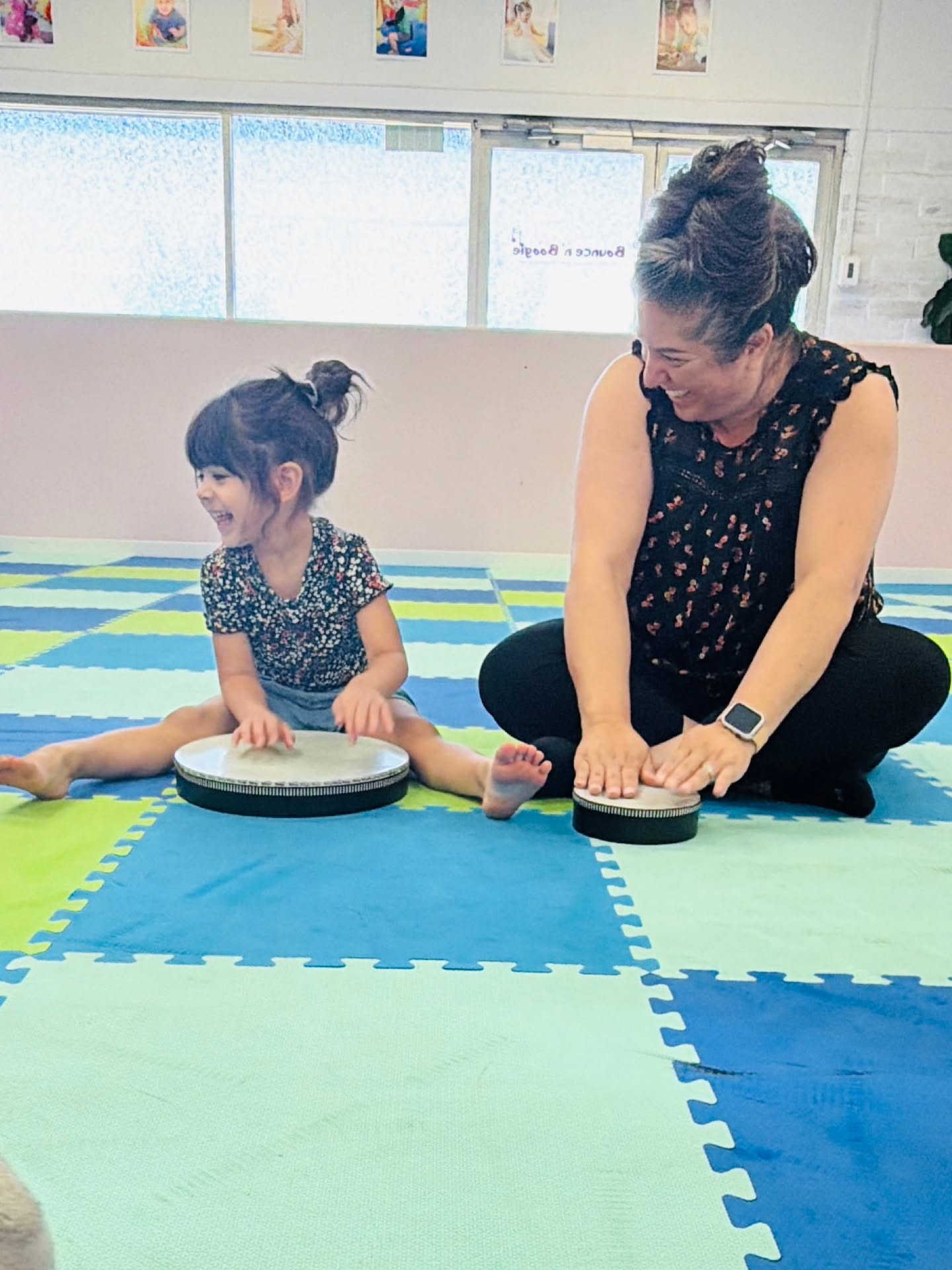 A teacher and a little girl playing drums together on the foam mats